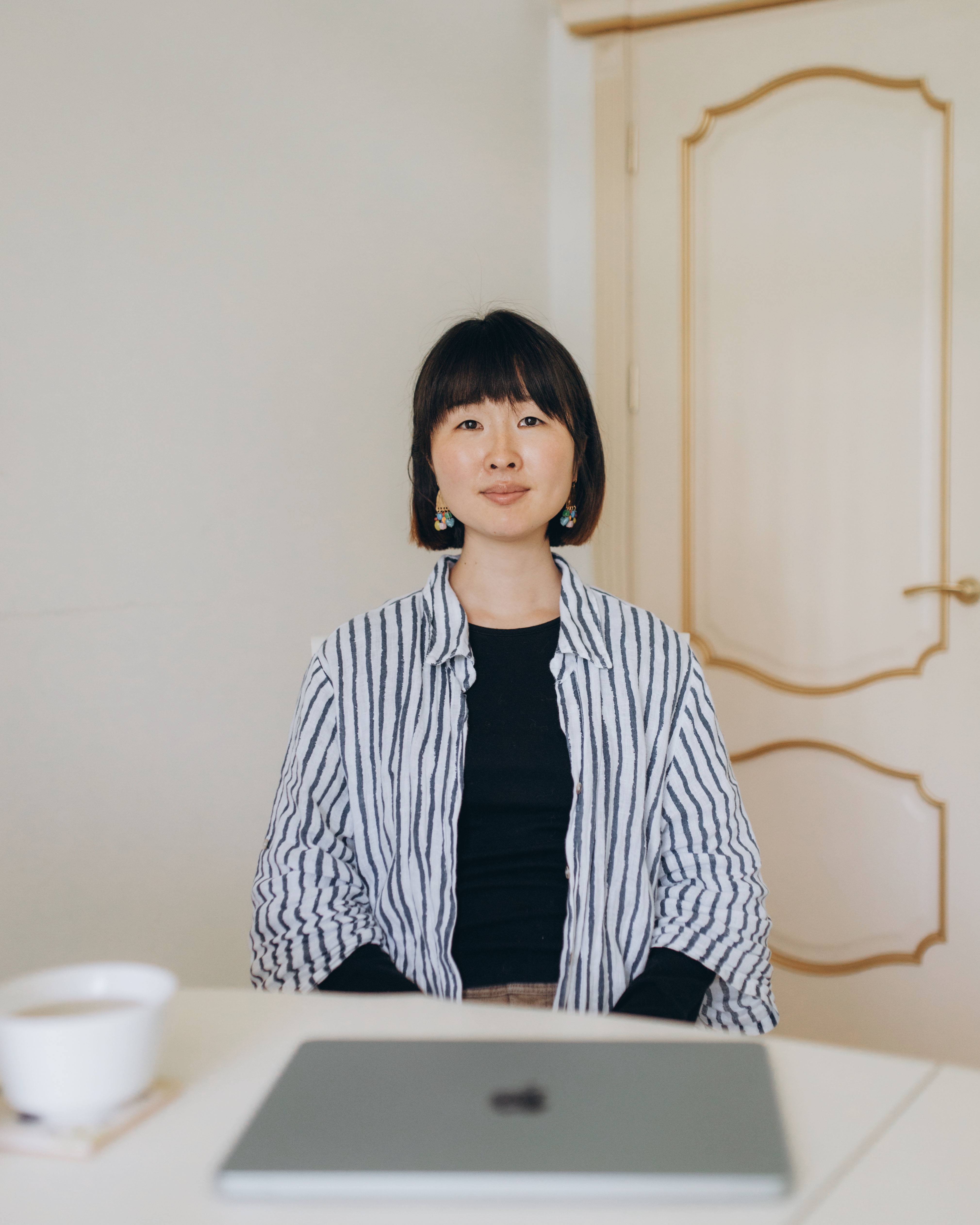 Sumire Sato standing at a table with a laptop and tea