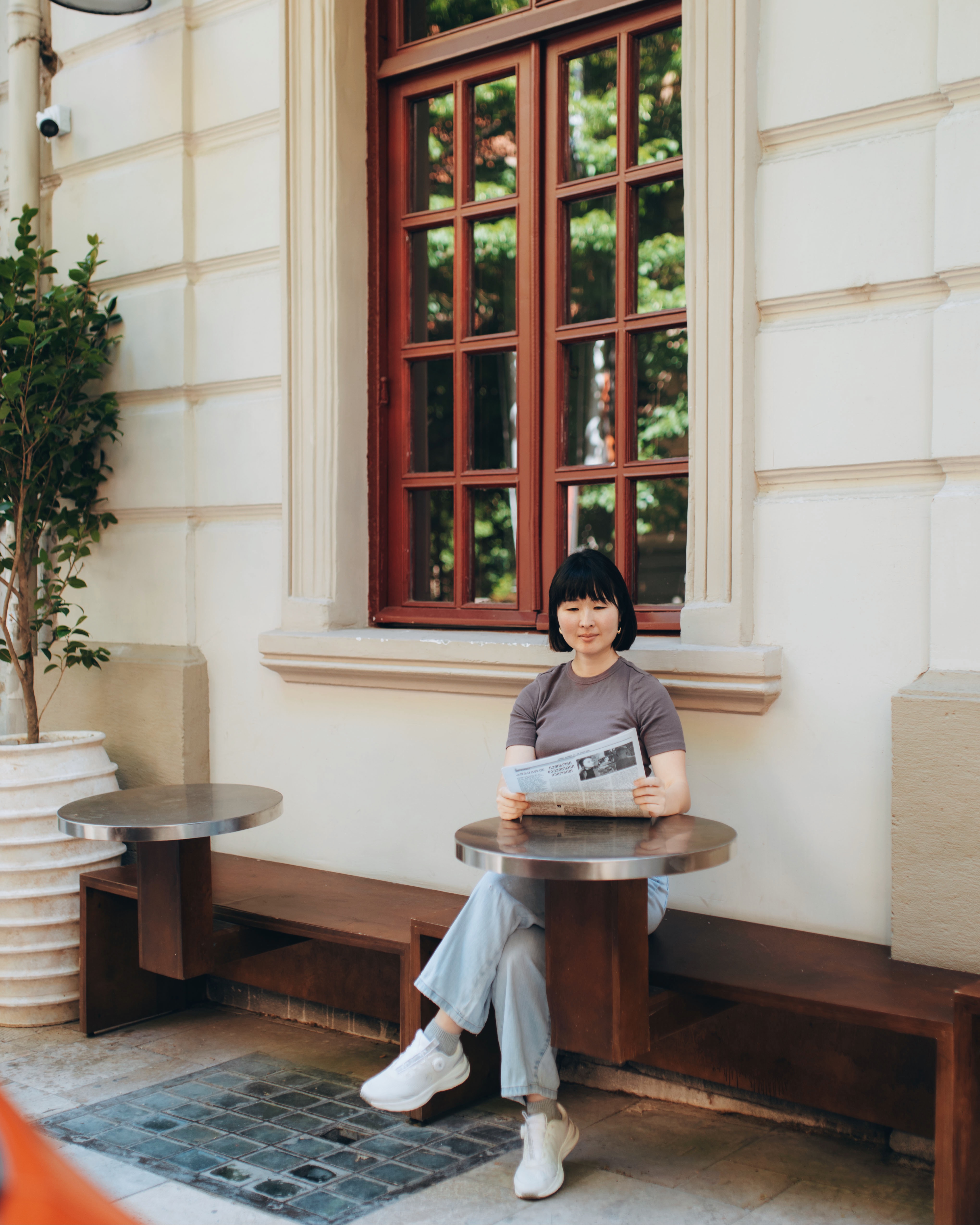 Sumire Sato reading a newspaper at an outdoor café table